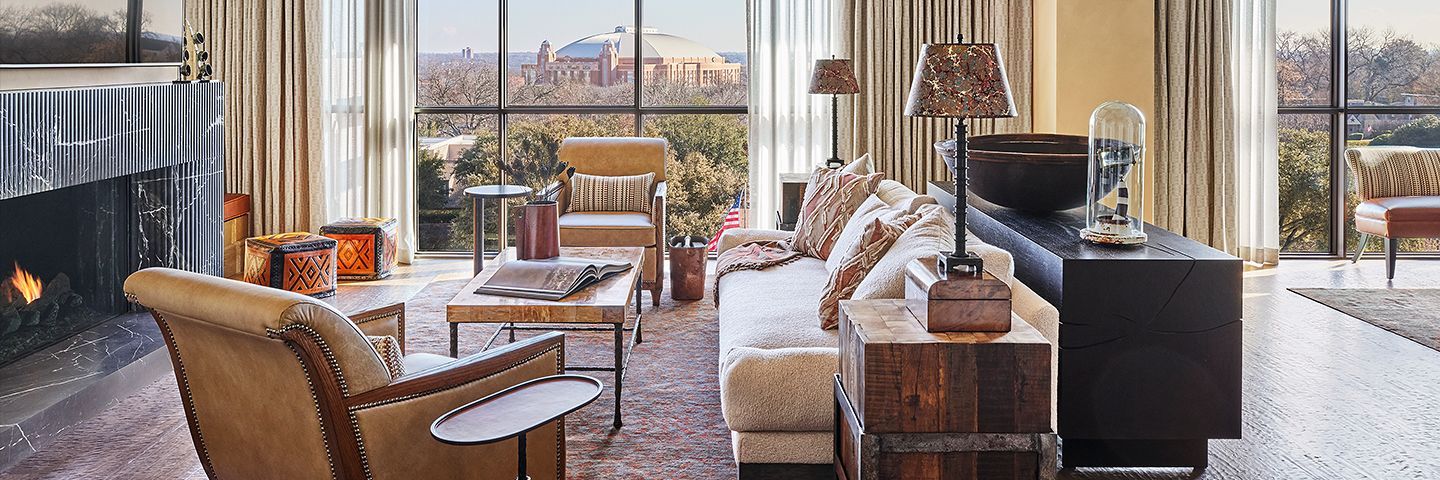 Elegant living room with tan leather chairs and a white sofa facing windows with a view of a domed stadium.