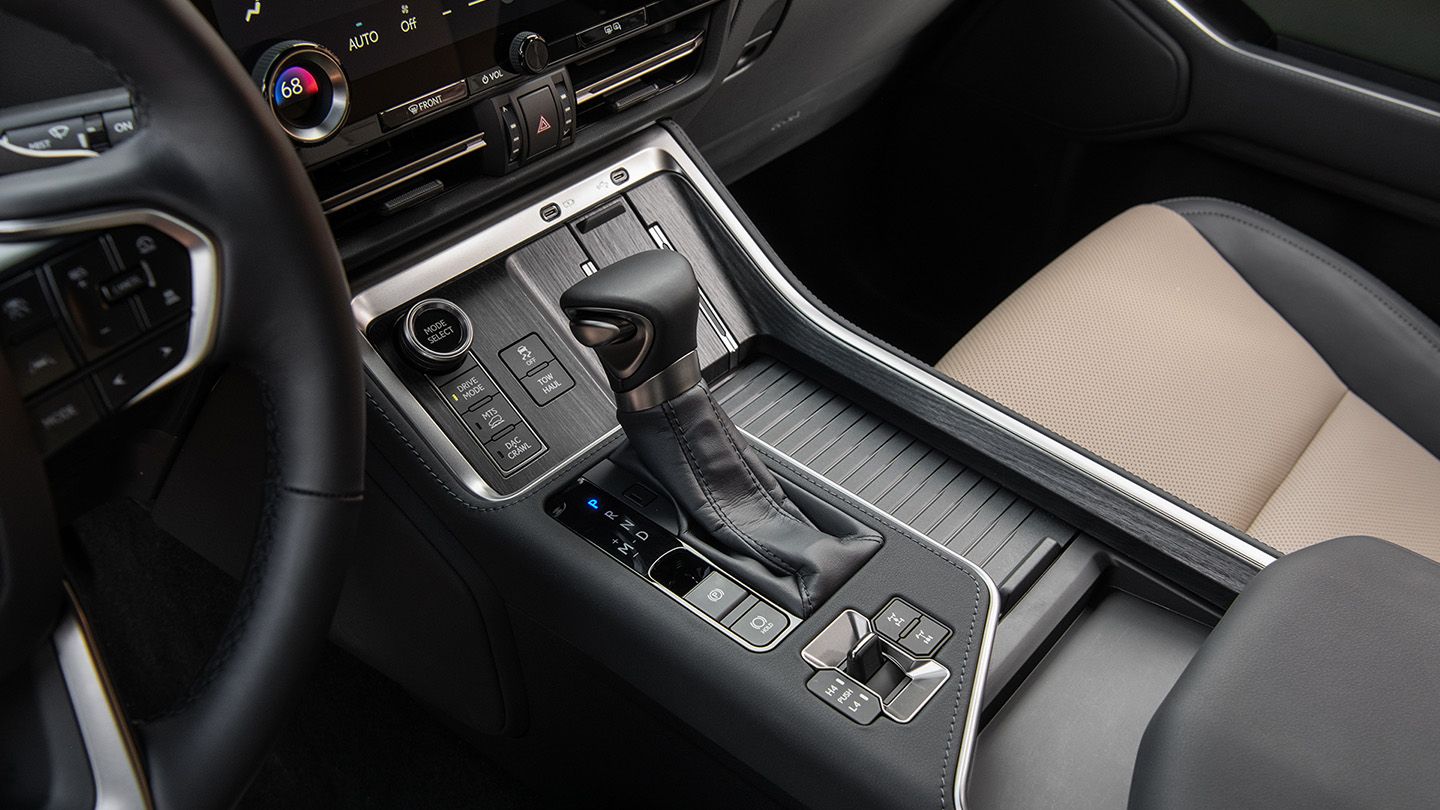 Close-up of front center console with roll-top cupholder cover, wireless charging tray and controls for four-wheel drive systems.